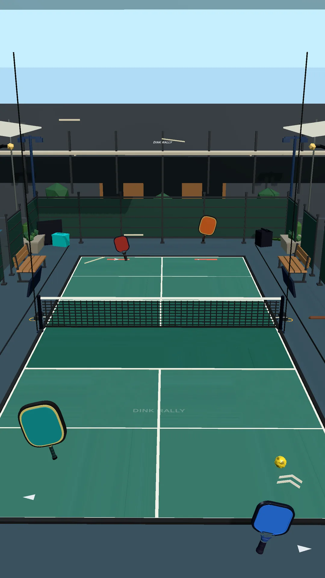 Dink Rally doubles serve from the player's end of the court, with two paddles ready, the ball in the air, and the venue stands beyond the far baseline.